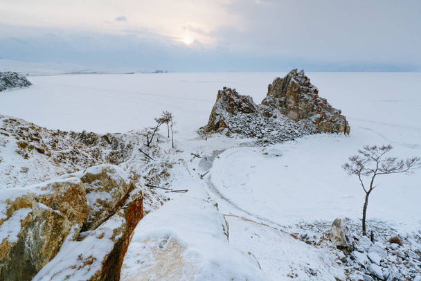 Vista de la roca Shamanka y el lago congelado Baikal durante el atardecer
 - Foto, imagen