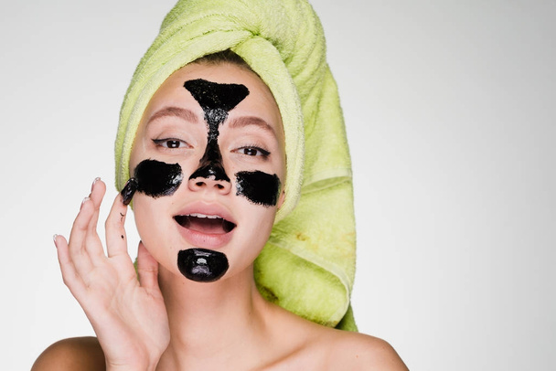 young girl with a towel on her head puts on face mask - Foto, Imagem