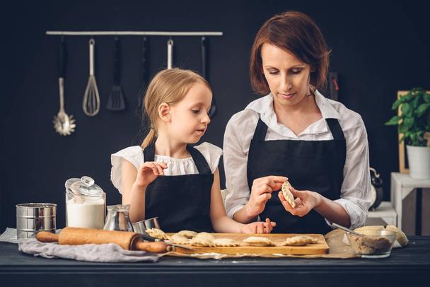 Mamma e figlia preparare gnocchi in cucina
 - Foto, immagini
