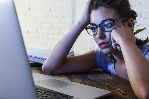 κουρασμένος μαθητής γυναίκα που εργάζεται σε φορητό υπολογιστή με το notepad αίσθημα απογοητευμένος και εξαντλημένος σπουδάζουν για εξετάσεις αργά τη νύχτα - Φωτογραφία, εικόνα