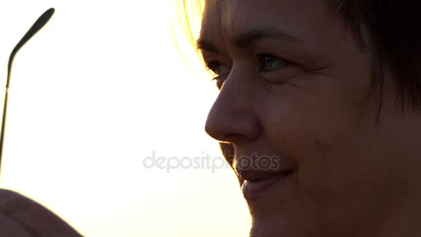 Mujer sonriente se pone sus gafas de sol en una orilla del lago en susnet
 - Metraje, vídeo