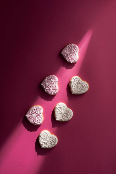 top view of glazed heart shaped cookies on pink tabletop - Fotó, kép