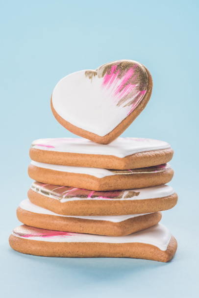 close up view of pile of glazed heart shaped cookies isolated on blue, st valentines day concept - Foto, imagen