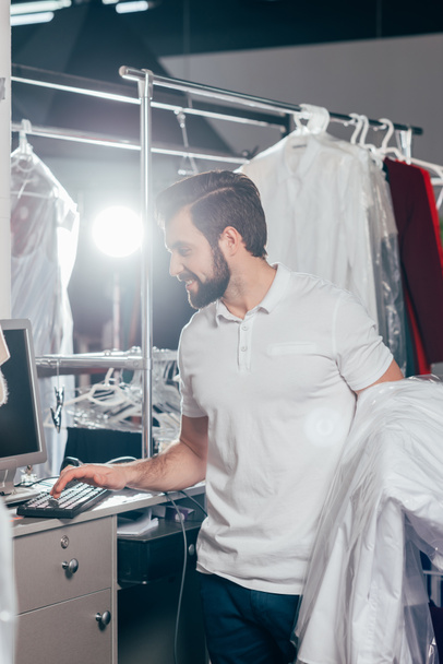 dry cleaning worker using computer at warehouse - Фото, зображення