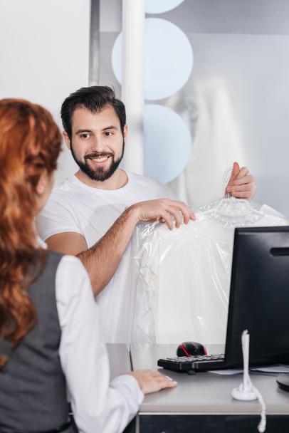 smiling dry cleaning manager giving order to customer - Foto, Bild