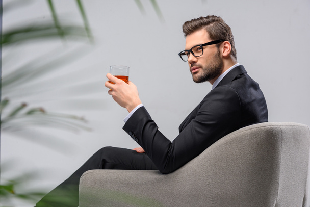 homme d'affaires assis dans un fauteuil avec un verre de whisky
 - Photo, image