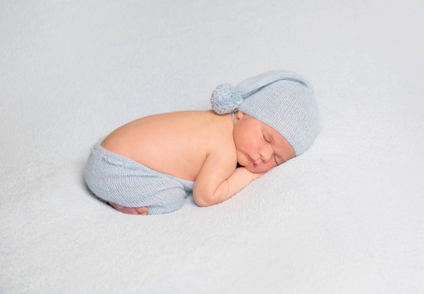Baby boy curled up on white blanket - Fotoğraf, Görsel