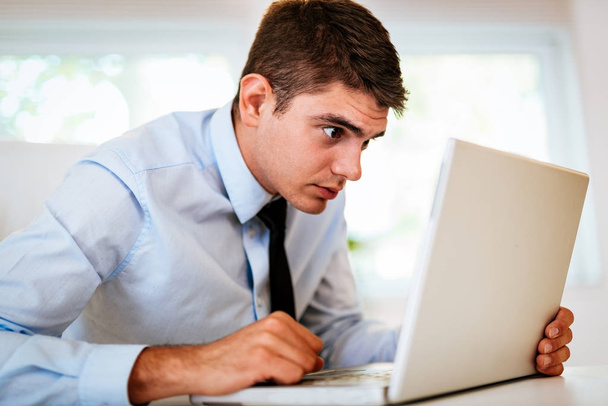 Młody podkreślił biznesmen worriedly patrząc na laptopie w biurze. - Zdjęcie, obraz