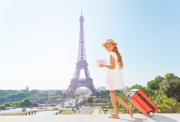 Preteen blond girl walking around Paris with suitcase and guide during summer vacation - Fotografie, Obrázek