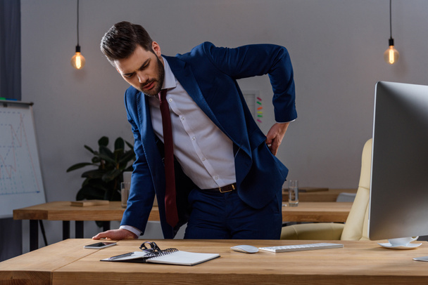 young businessman in suit having pain in back - Photo, image
