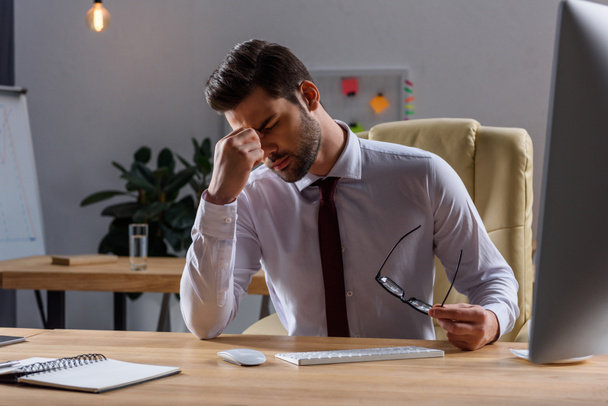 sick businessman having headache while working in evening at office - Photo, image