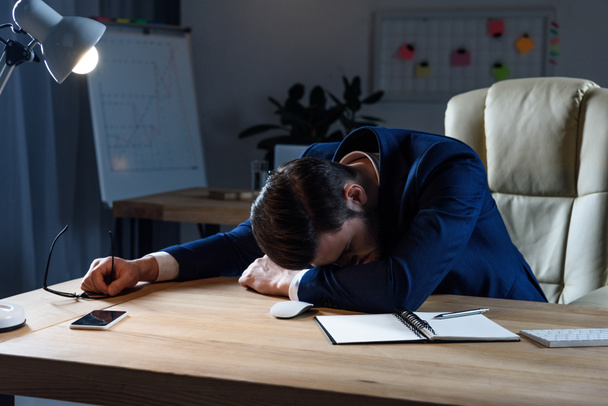 tired businessman in suit sleeping at working table - Foto, Imagem