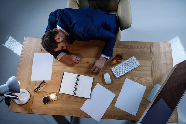 overhead view of businessman sleeping at working table - Photo, Image