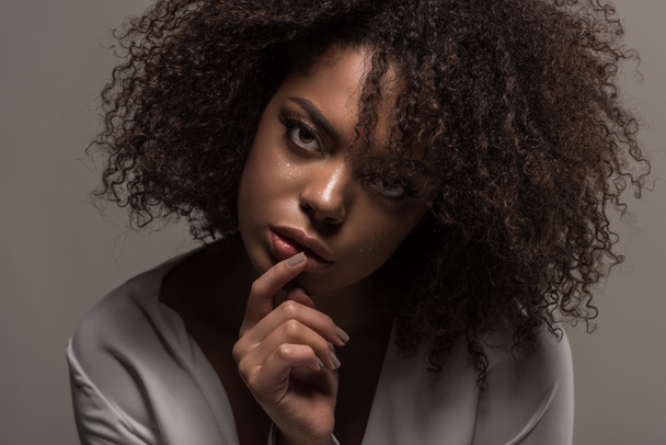 灰色の背景で隔離の唇に手と白いシャツで官能的なアフリカ系アメリカ人女性 - 写真・画像