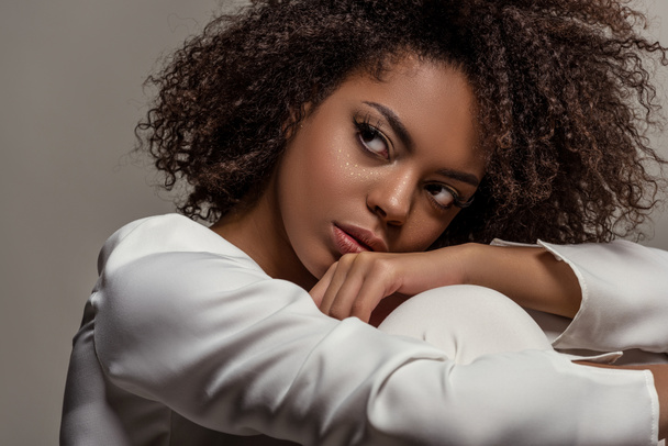 Joven mujer afroamericana sensual en camisa blanca mirando hacia otro lado aislado sobre fondo gris
 - Foto, imagen