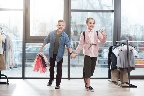 niños felices con bolsas de compras haciendo selfie en la tienda
 - Foto, imagen
