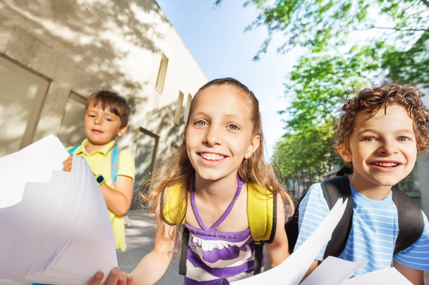 Close portrait of the girl in the group hold papers and smile to camera - Photo, Image