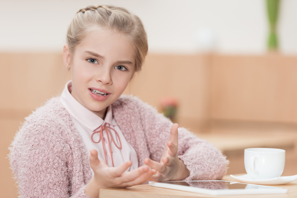 child sitting at table with digital tablet and looking at camera  - Photo, Image