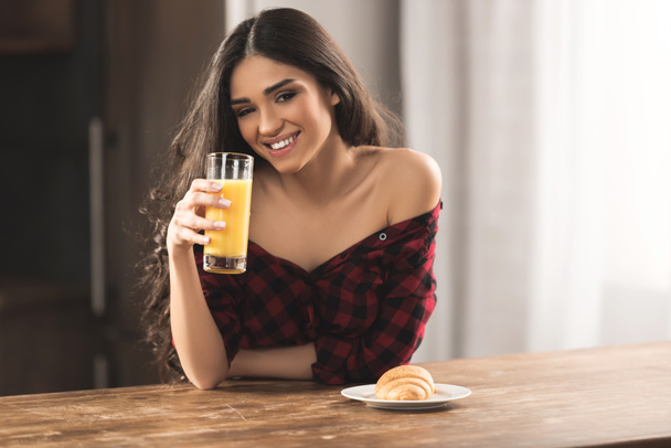 sexy girl in checkered shirt eating croissant and drinking orange juice for breakfast  - Foto, afbeelding