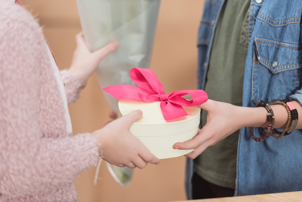 обрезанный образ мальчика, дарящего букет и коробку с лентой девушке
 - Фото, изображение