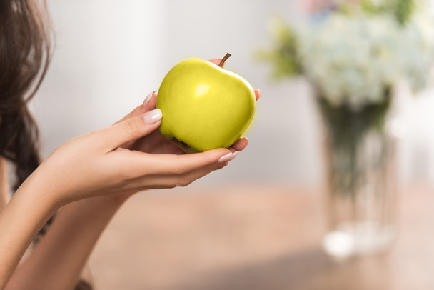 close-up partial view of girl holding fresh green apple - Fotografie, Obrázek