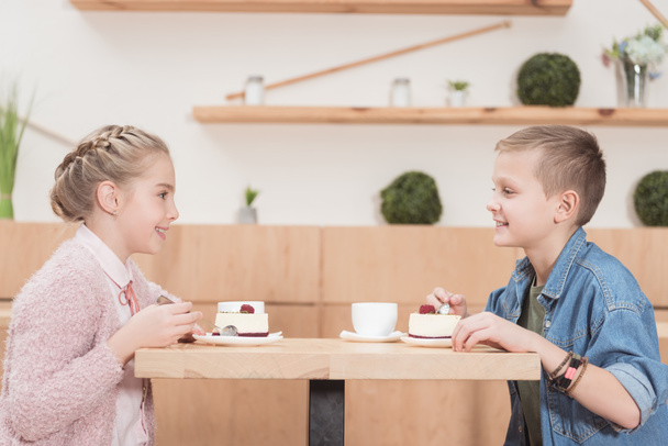 children sitting at table at cafe while looking at each other and smiling   - Photo, Image