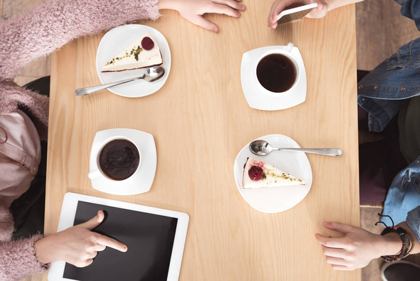 imagen recortada de los niños sentados en la mesa con aparatos en la superficie en la cafetería
  - Foto, Imagen