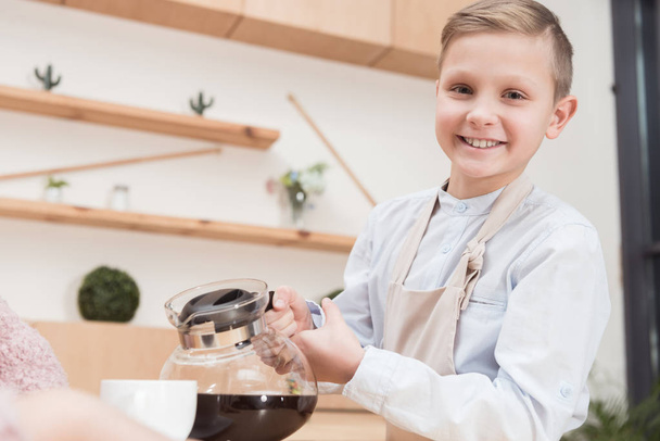 smiling  boy holding pot with coffee in hands at cafe  - Fotoğraf, Görsel