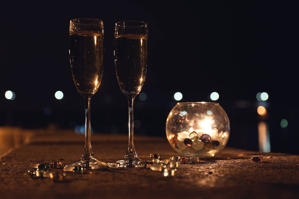 Романтическая композиция с горящими свечами и бокалами шампанского ночью, на открытом воздухе
 - Фото, изображение