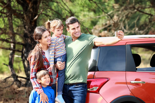 Szczęśliwa rodzina biorąc selfie w pobliżu nowoczesnego samochodu na zewnątrz - Zdjęcie, obraz