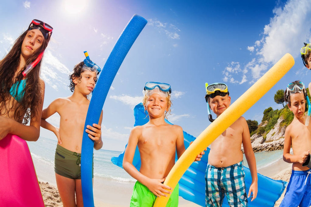 Group of kids on the beach with swimming sticks on hot summer day - Photo, image