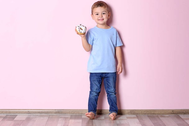 Little boy with sweet donut near color wall - Photo, image