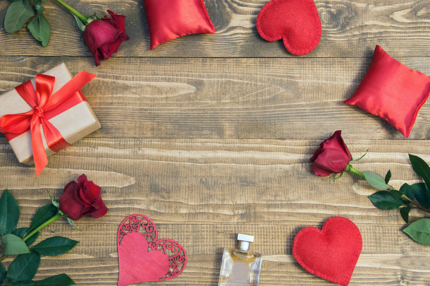 Valentine's day background with love gift, red roses, perfume and heart shapes. View from above. Copy space. - 写真・画像