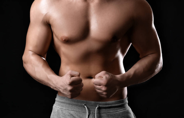 Muscular young bodybuilder on dark background - Foto, Imagem