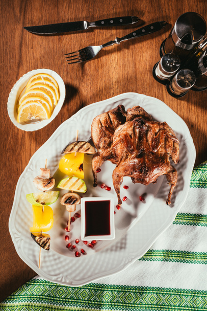 Peçete ile ahşap masa üzerinde kızarmış tavukla plaka üzerinde ızgara sebze Üstten Görünüm - Fotoğraf, Görsel