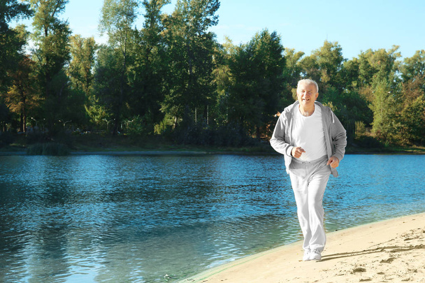 Volwassen man loopt in de buurt van rivier - Foto, afbeelding