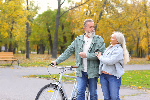 Старша пара гуляє з велосипедом у парку
 - Фото, зображення