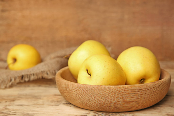 Wooden plate with ripe yellow apples on table - Φωτογραφία, εικόνα