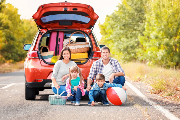 Счастливая семья рядом с машиной на дороге
 - Фото, изображение