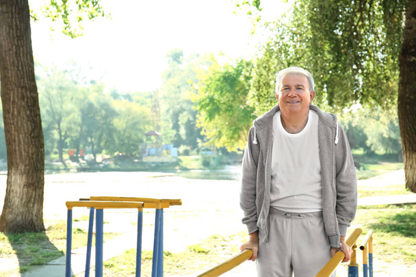 Mature man doing exercise in park - Photo, Image