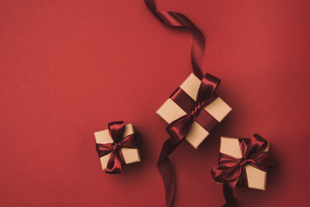 flat lay with arrangement of gifts decorated with ribbons isolated on red - Fotografie, Obrázek