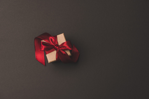 top view of gift box with red ribbon isolated on dark surfae - Foto, Imagem