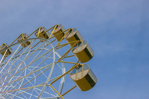 Roda gigante com cabines redondas amarelas contra o céu azul no summ
 - Foto, Imagem