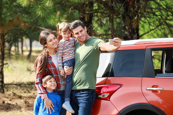 Famille heureuse prendre selfie près de voiture moderne à l'extérieur
 - Photo, image