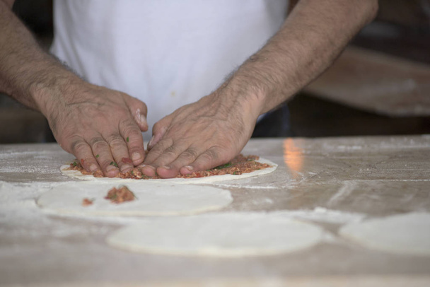Adam Lahmacun hamuru mutfak masasında elleriyle hazırlanıyor - Fotoğraf, Görsel