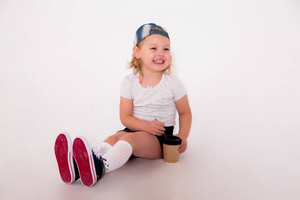 küçük kızla bir kahve cam onun elinde bir spor tarzda - Fotoğraf, Görsel