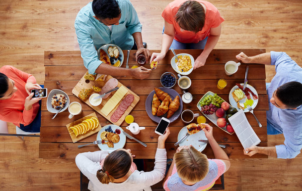 people with smartphones eating food at table - Fotó, kép