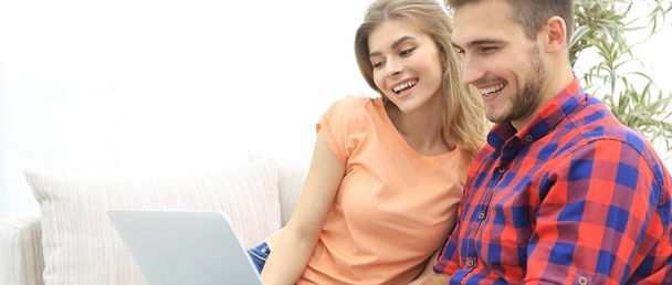 smiling young couple with laptop sitting on the couch - Photo, Image