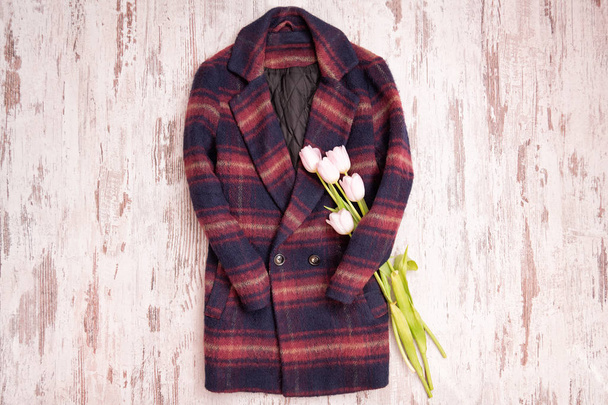 温かみのある市松模様のコートとチューリップ。ファッショナブルな概念、木製の背景 - 写真・画像