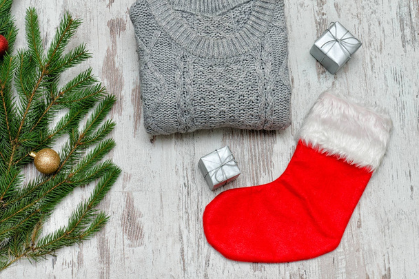 Red Christmas sock and a gray sweater. Decorated fir branch - Photo, Image